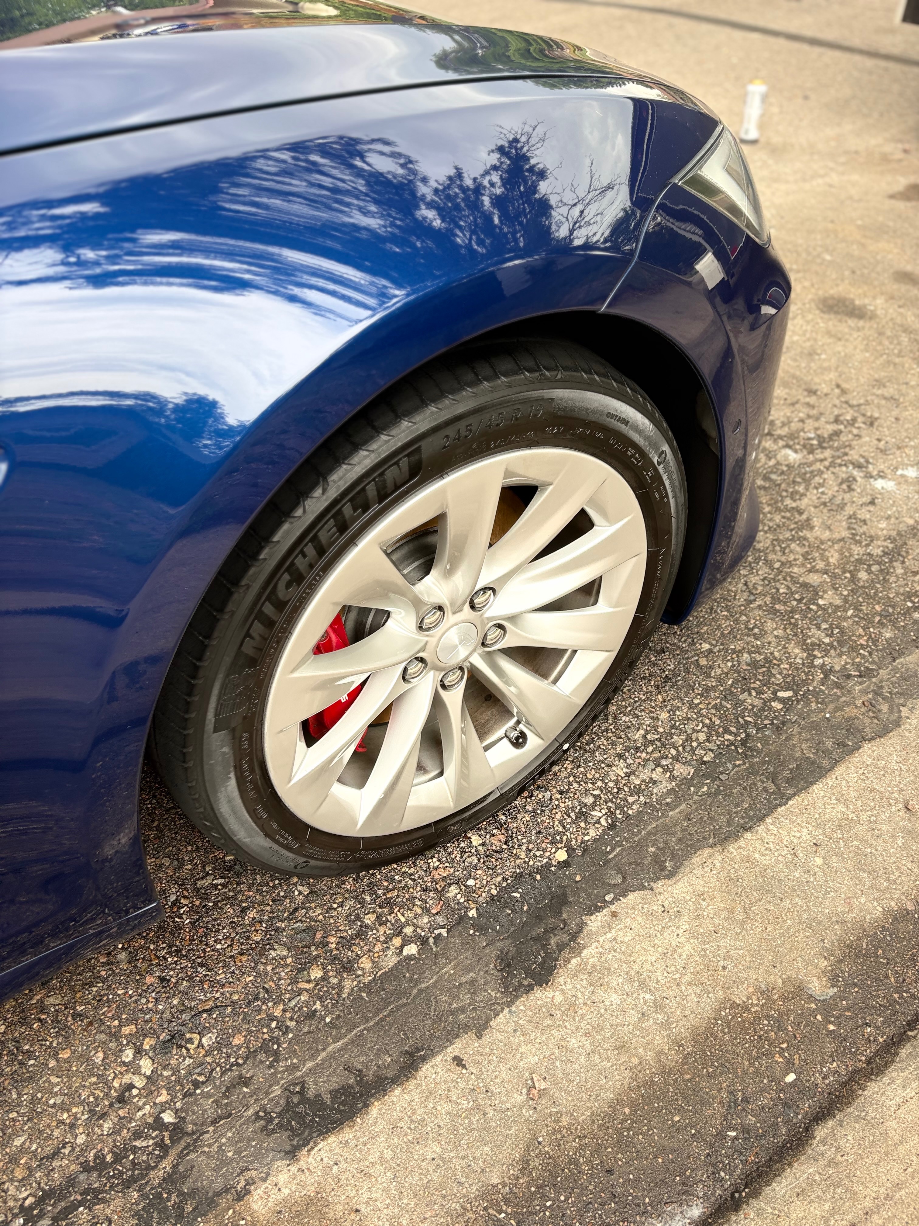 Blue Tesla fender and polished wheel with a red brake caliper